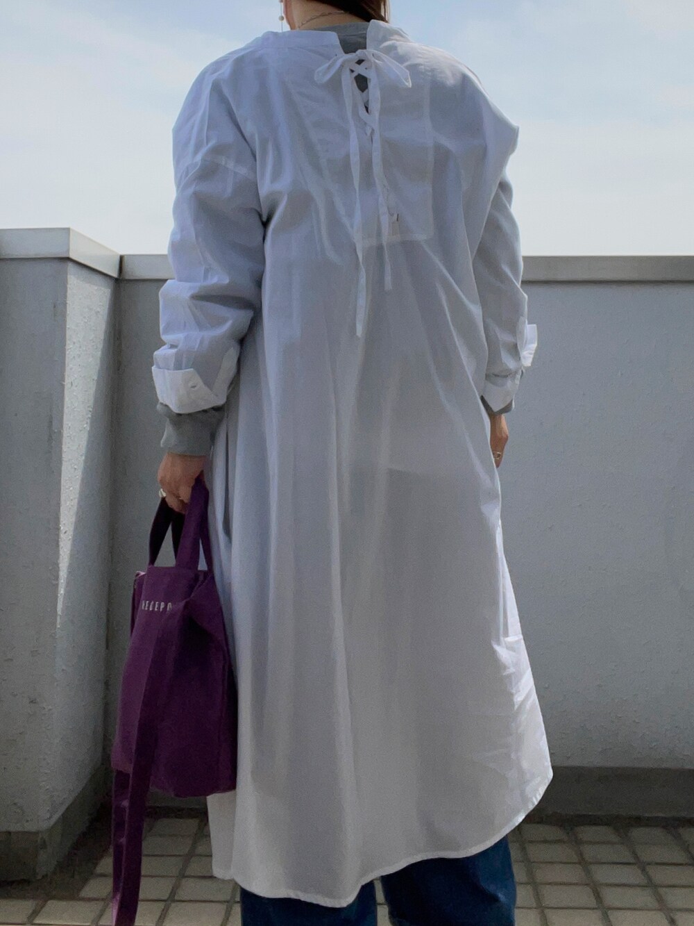 グレー系のスウェット、ホワイト系のワンピース、パープル系のトートバッグを着用したレディースの春コーディネートの4枚目の写真