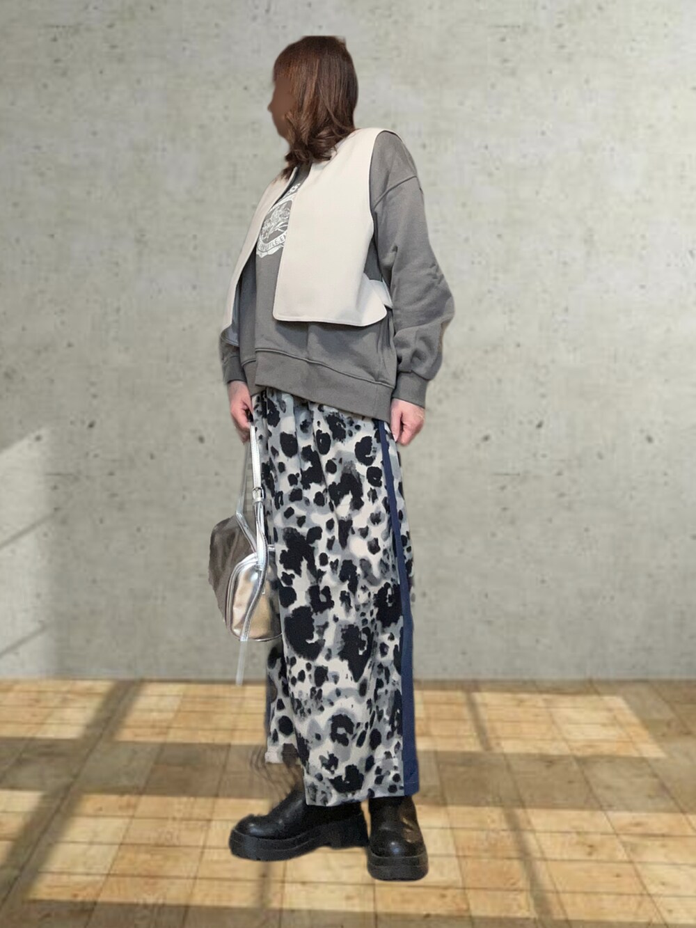 ベージュ系のステンカラーコート、グレー系のスウェット、ブラック系のスカートを着用したレディースの冬コーディネートの2枚目の写真