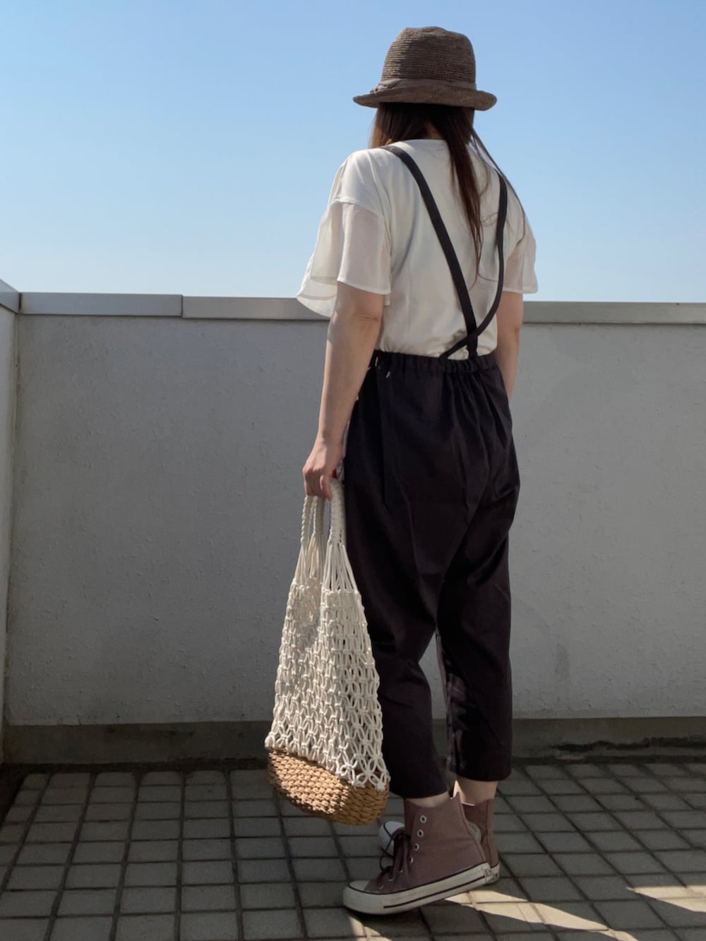 ブラウン系のスニーカー、ホワイト系のかごバッグ、ブラウン系のハットを着用したレディースの夏コーディネートの3枚目の写真