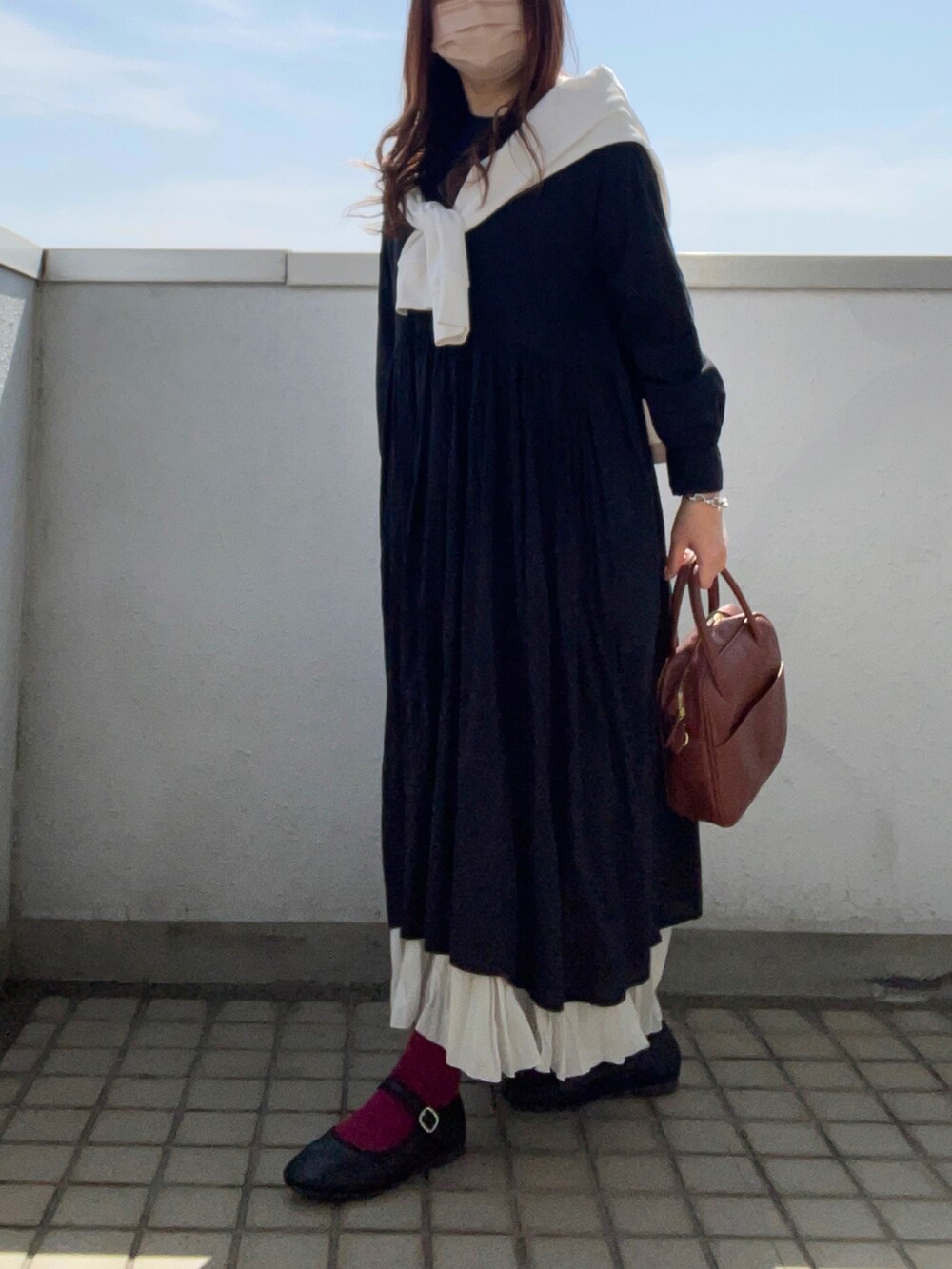 ブラック系のワンピース、ブラウン系のボストンバッグ、グレー系のスカートを着用したレディースの春コーディネートの2枚目の写真