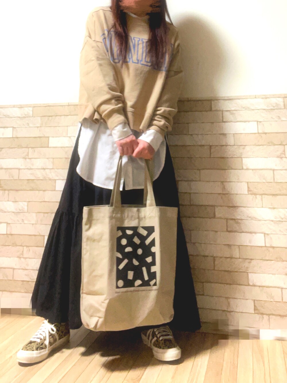 ベージュ系のスウェット、ホワイト系のシャツ/ブラウス、ブラック系のスカートを着用したレディースの春コーディネートの2枚目の写真