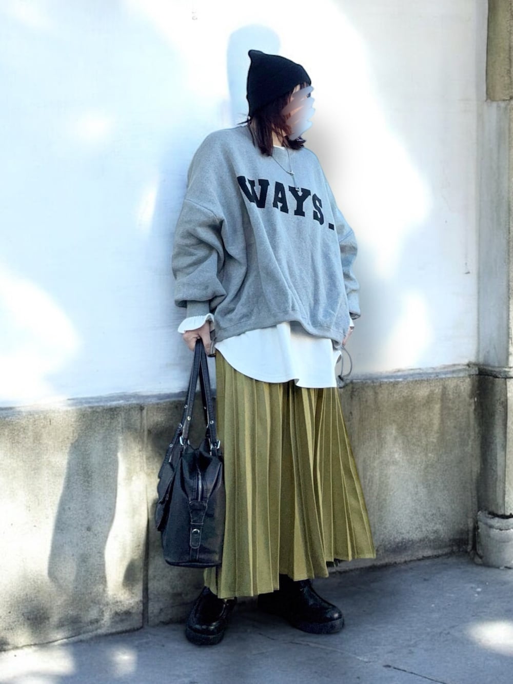 イエロー系のスカート、グレー系のニット/セーター、ホワイト系のTシャツ/カットソーを着用したレディースの冬コーディネートの2枚目の写真