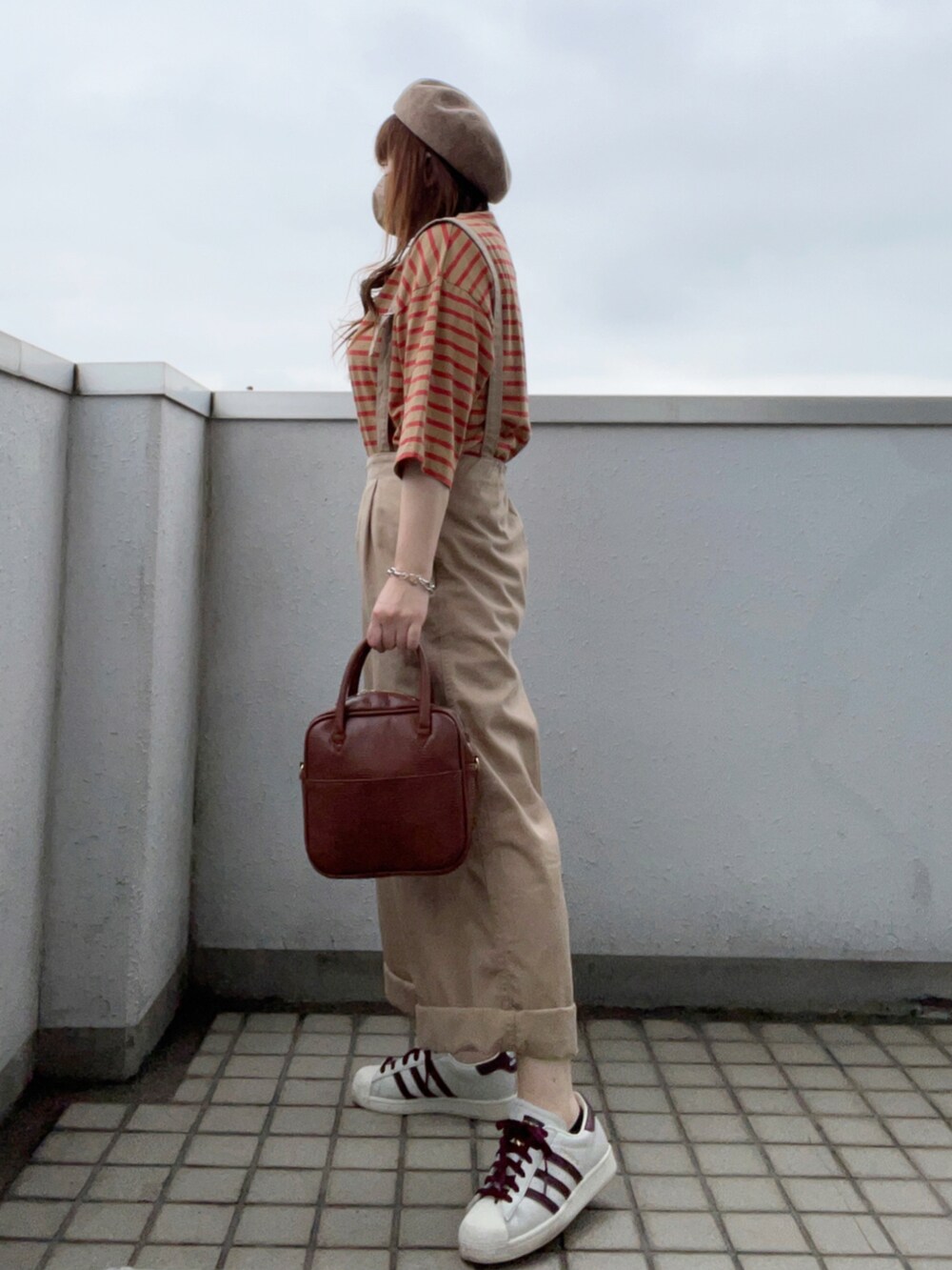 イエロー系のTシャツ/カットソー、ブラウン系のボストンバッグ、ホワイト系のスニーカーを着用したレディースの夏コーディネートの3枚目の写真