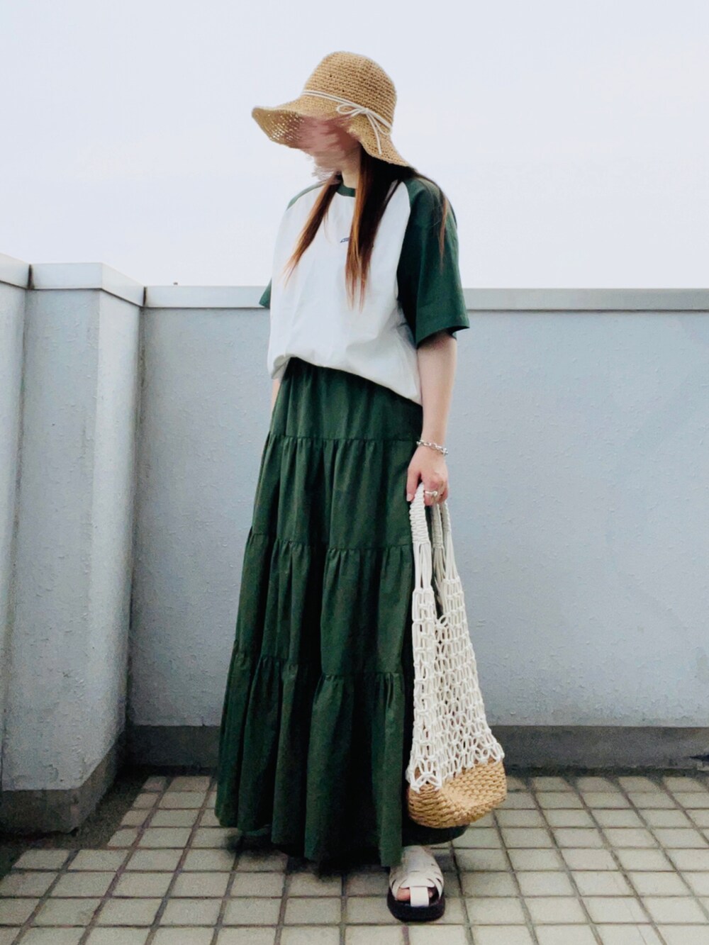 グリーン系のTシャツ/カットソー、グリーン系のスカート、ホワイト系のかごバッグを着用したレディースの夏コーディネートの2枚目の写真