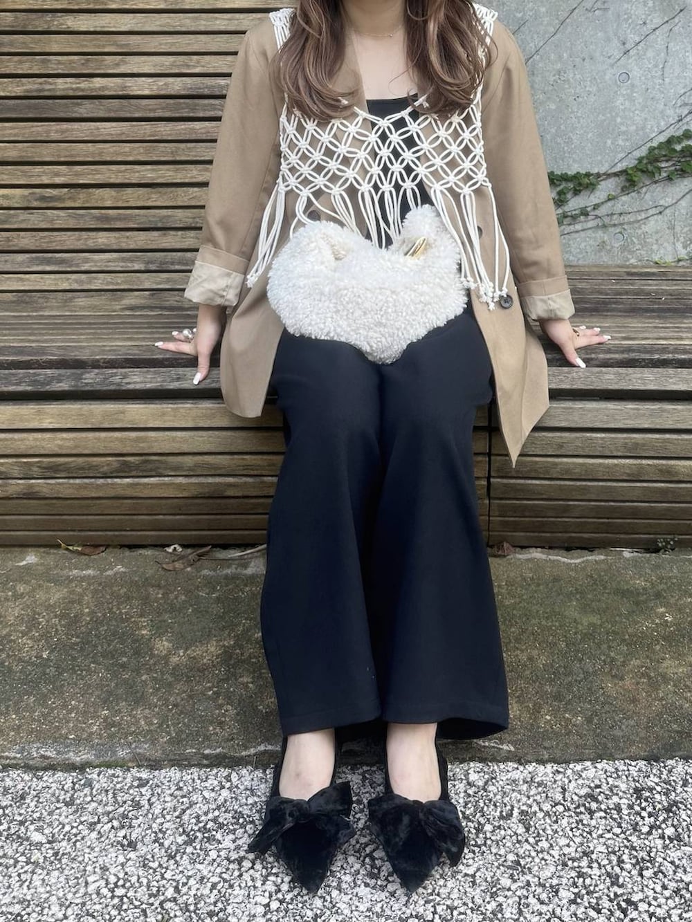 ブラック系のパンプス、ホワイト系のハンドバッグ、ブラック系のスラックスを着用したレディースの秋コーディネートの2枚目の写真