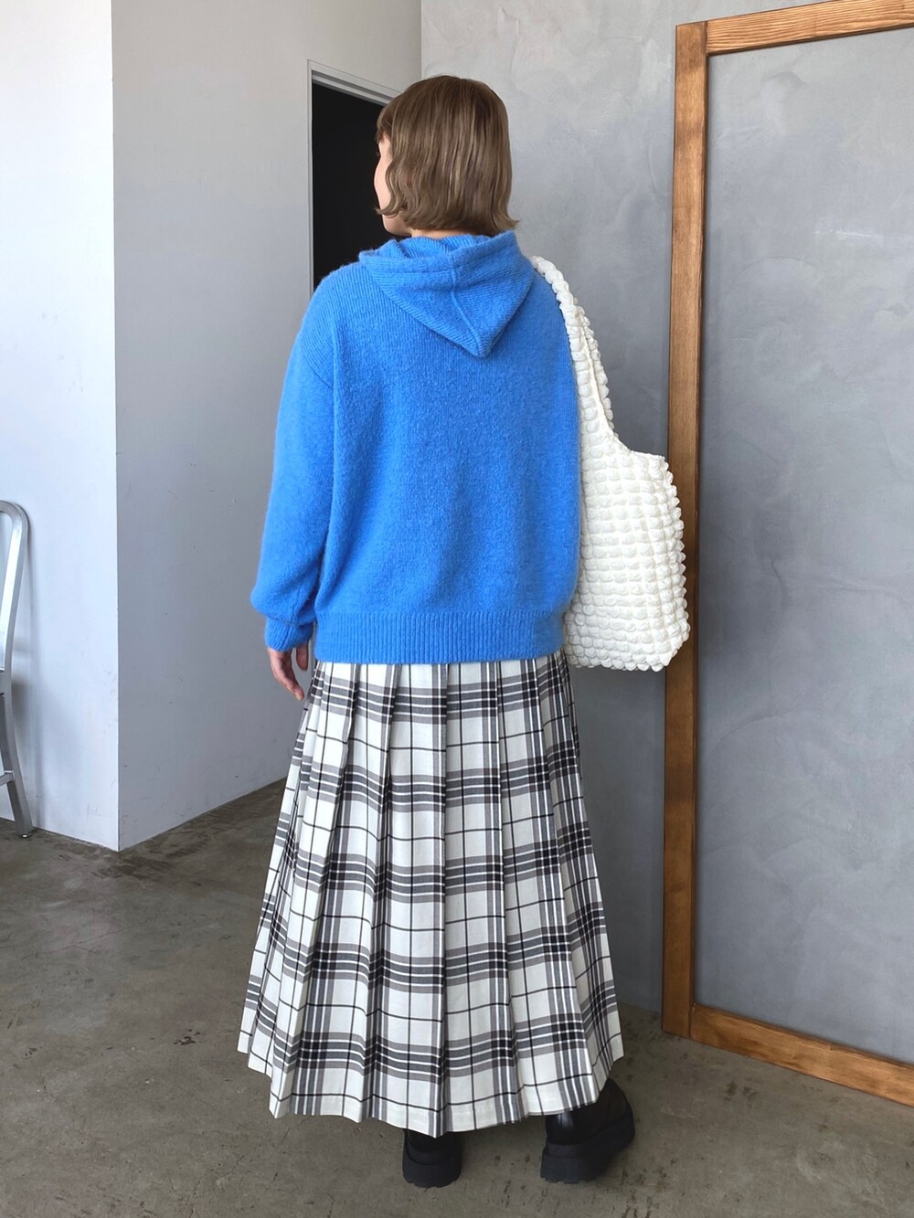 ブルー系のニット/セーター、ホワイト系のスカート、ブラック系のブーツを着用したレディースの秋コーディネートの4枚目の写真