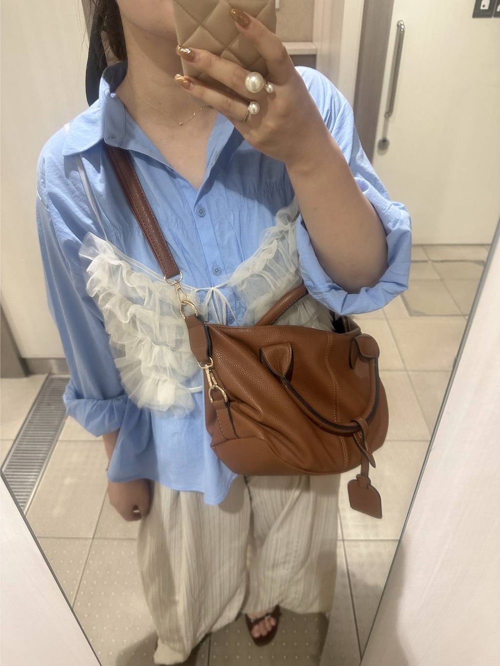 ブラウン系のボストンバッグ、ブルー系のシャツ/ブラウスを着用したレディースの秋コーディネートの3枚目の写真