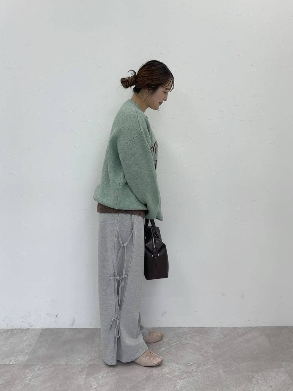 グリーン系のニット/セーター、グレー系のスウェットパンツ、ブラウン系のショルダーバッグを着用したレディースの秋コーディネートの2枚目の写真