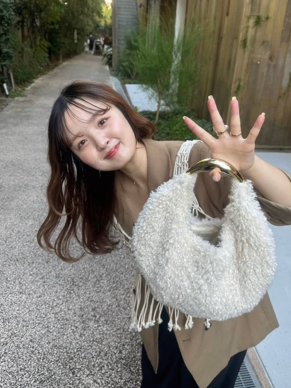 ブラック系のパンプス、ホワイト系のハンドバッグ、ブラック系のスラックスを着用したレディースの秋コーディネートの4枚目の写真