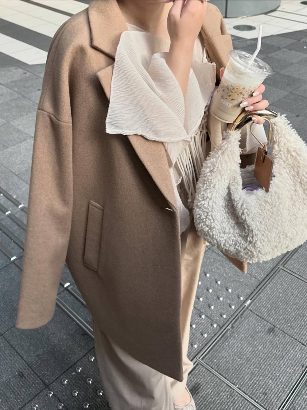 ベージュ系のチェスターコート、ベージュ系のスラックス、ホワイト系のハンドバッグを着用したレディースの秋コーディネートの5枚目の写真