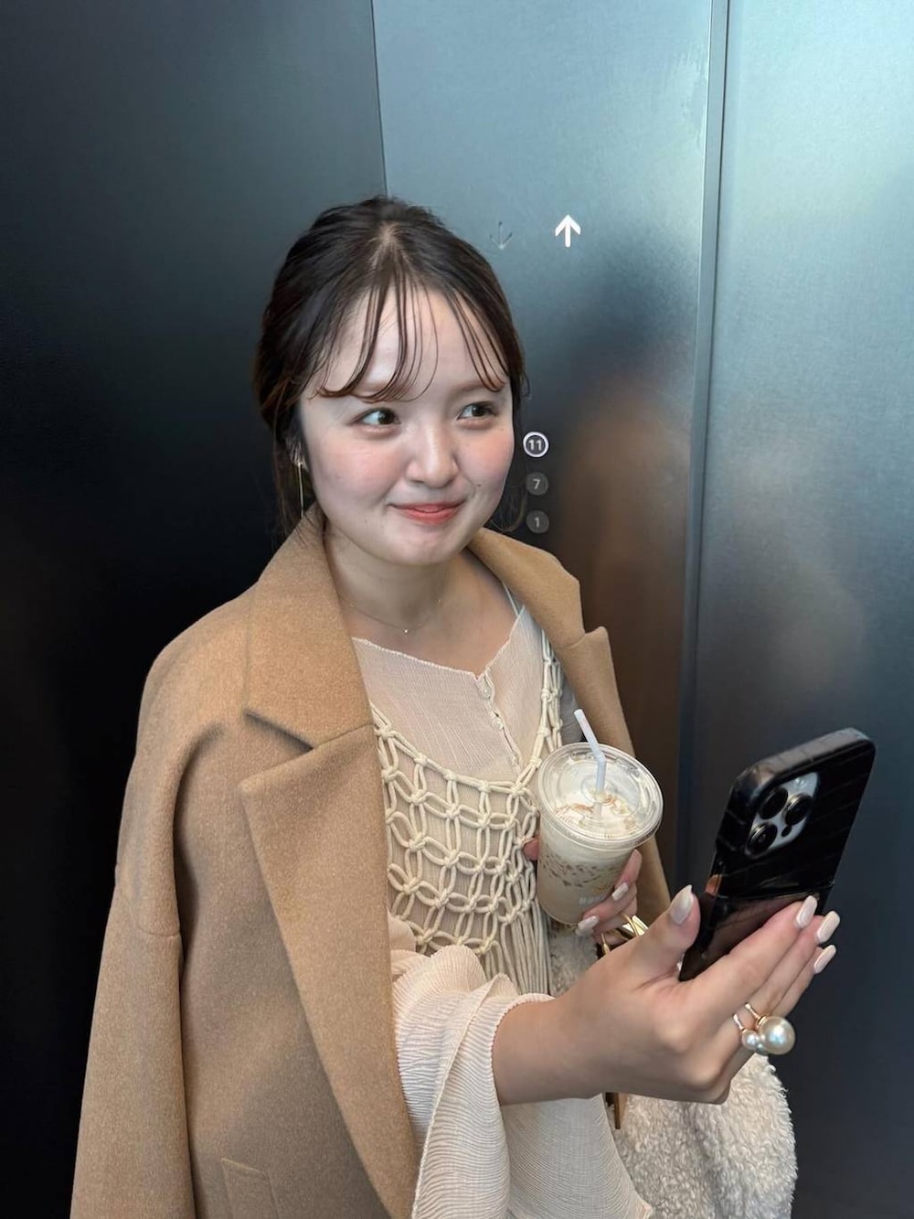 ベージュ系のチェスターコート、ベージュ系のスラックス、ホワイト系のハンドバッグを着用したレディースの秋コーディネートの3枚目の写真