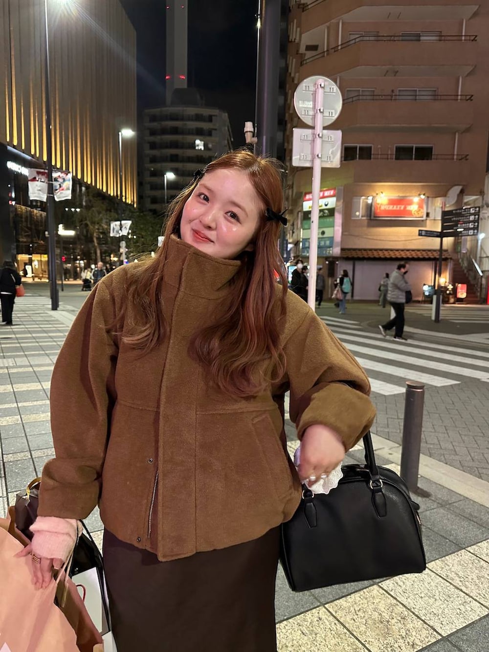 ブラウン系のスカート、ブラック系のボストンバッグ、ブラウン系のブルゾンを着用したレディースの秋コーディネートの2枚目の写真