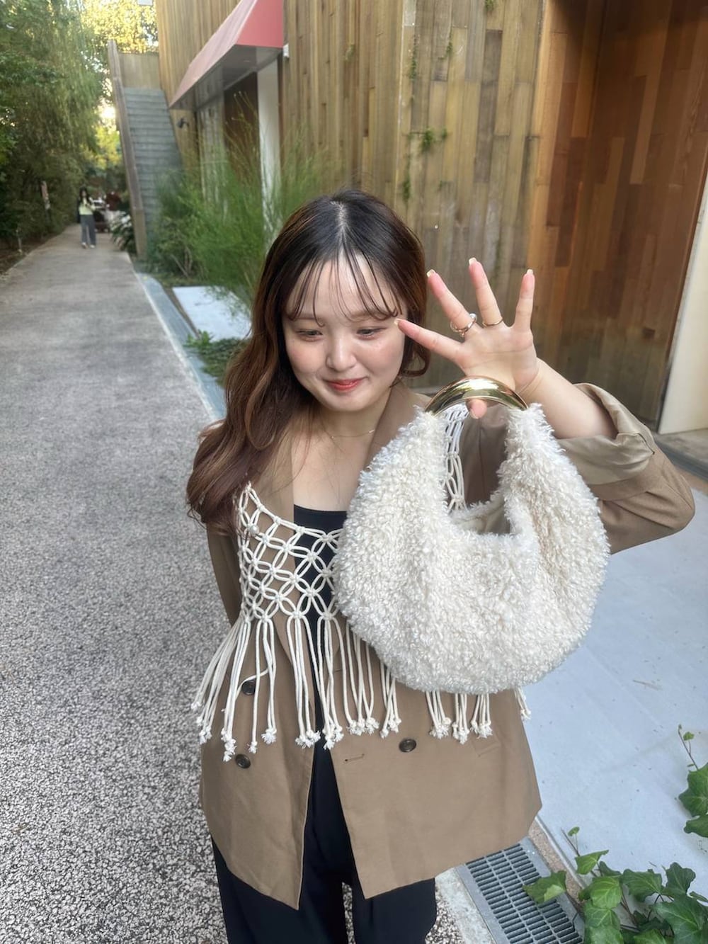 ブラック系のパンプス、ホワイト系のハンドバッグ、ブラック系のスラックスを着用したレディースの秋コーディネートの3枚目の写真