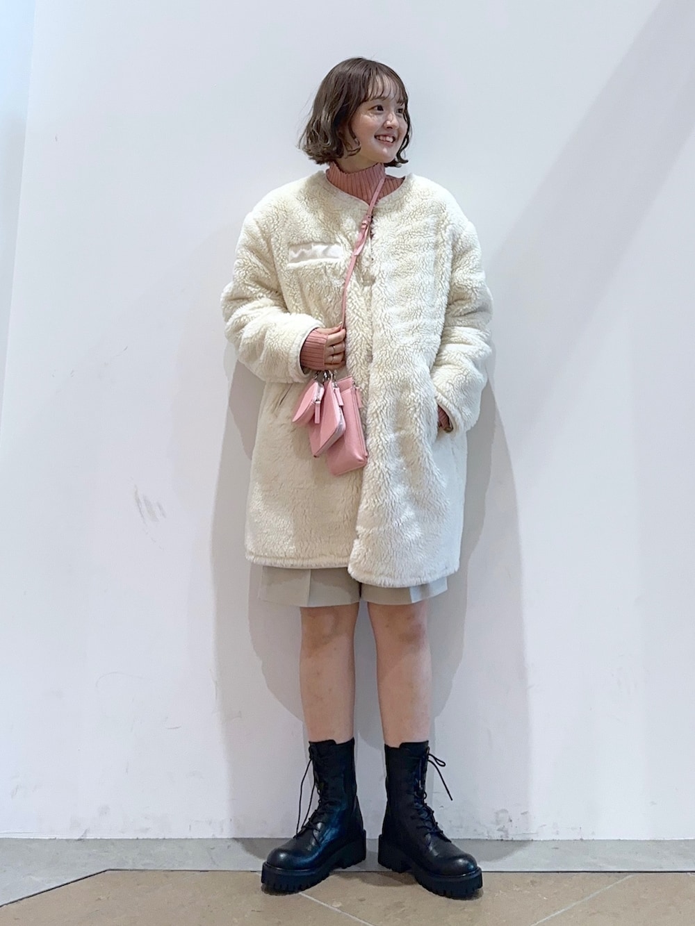 ホワイト系のミリタリージャケット、ホワイト系のパンツ、ブラック系のブーツを着用したレディースの秋コーディネートの2枚目の写真