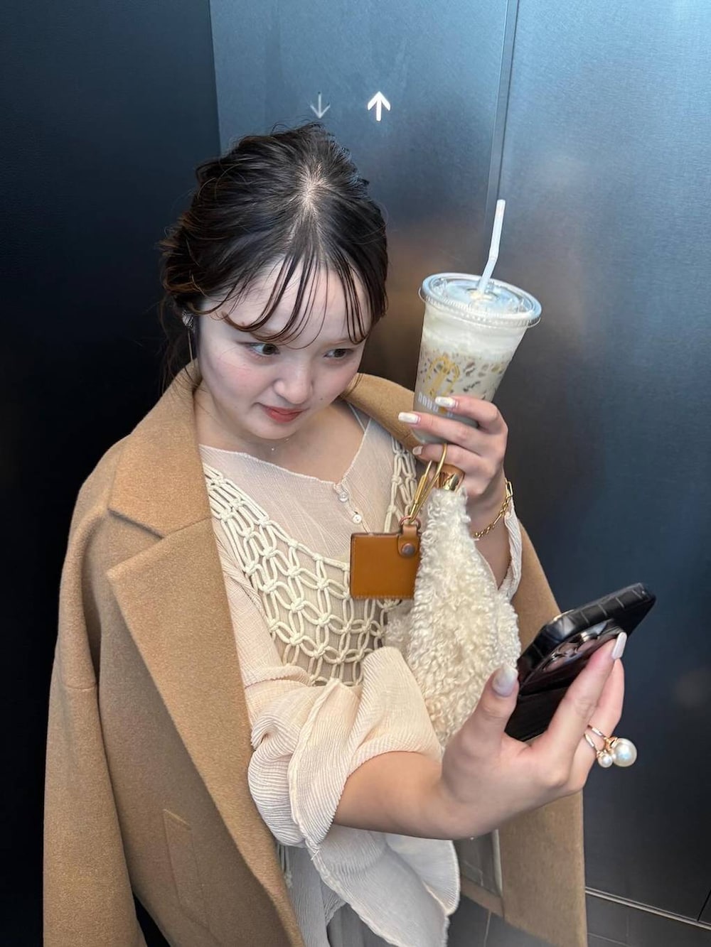 ベージュ系のチェスターコート、ベージュ系のスラックス、ホワイト系のハンドバッグを着用したレディースの秋コーディネートの4枚目の写真