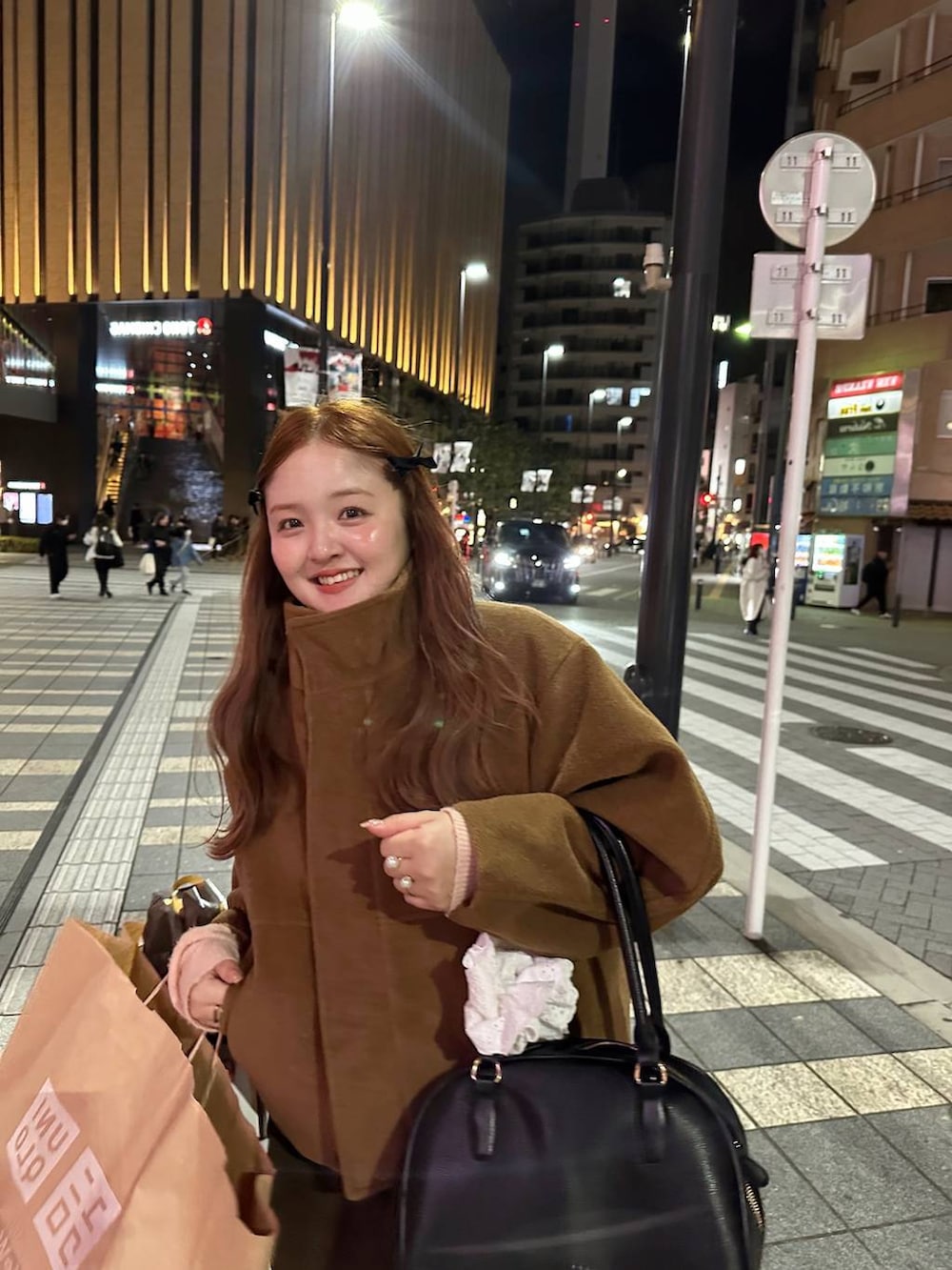 ブラウン系のスカート、ブラック系のボストンバッグ、ブラウン系のブルゾンを着用したレディースの秋コーディネートの5枚目の写真