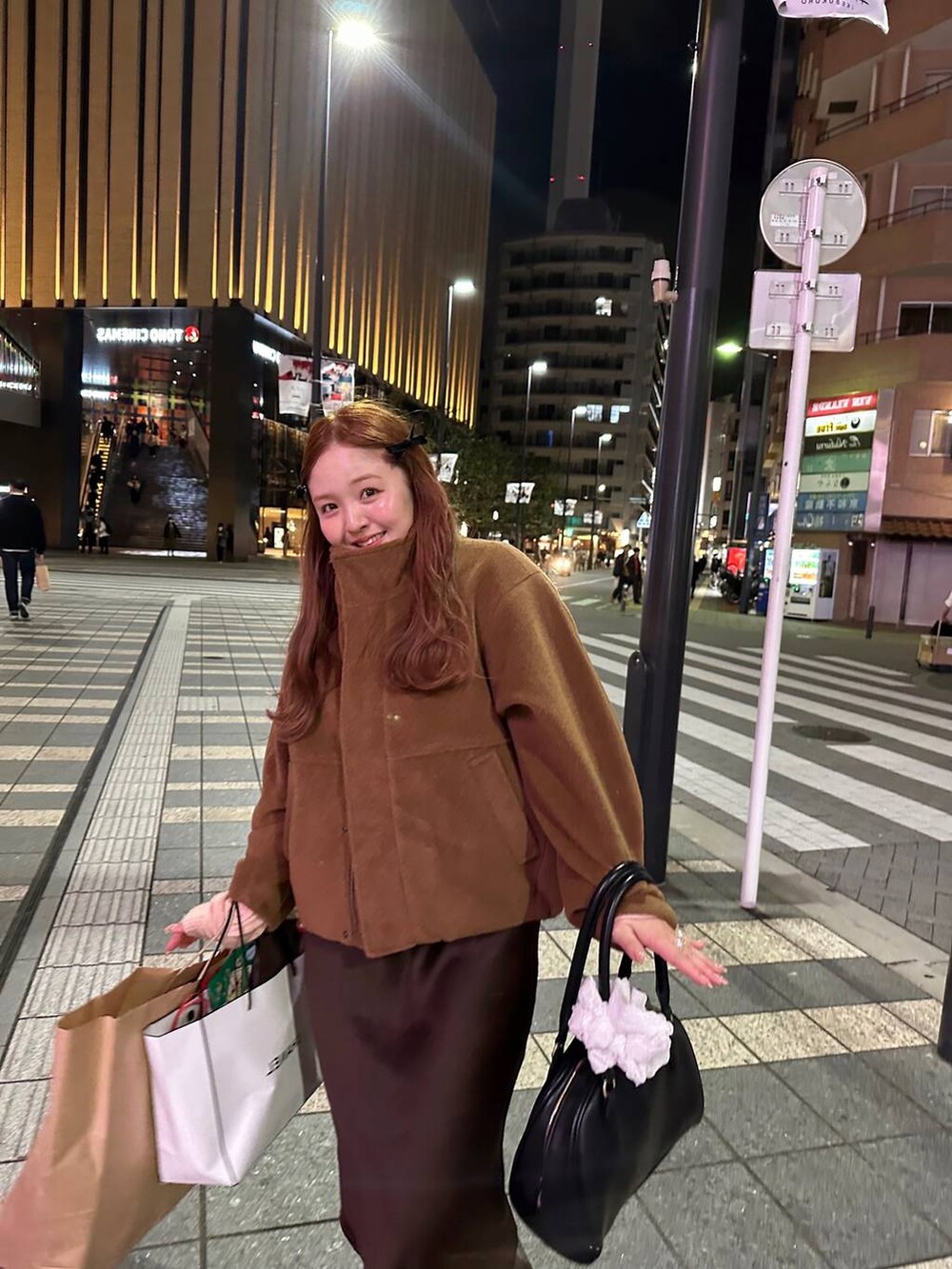 ブラウン系のスカート、ブラック系のボストンバッグ、ブラウン系のブルゾンを着用したレディースの秋コーディネートの4枚目の写真