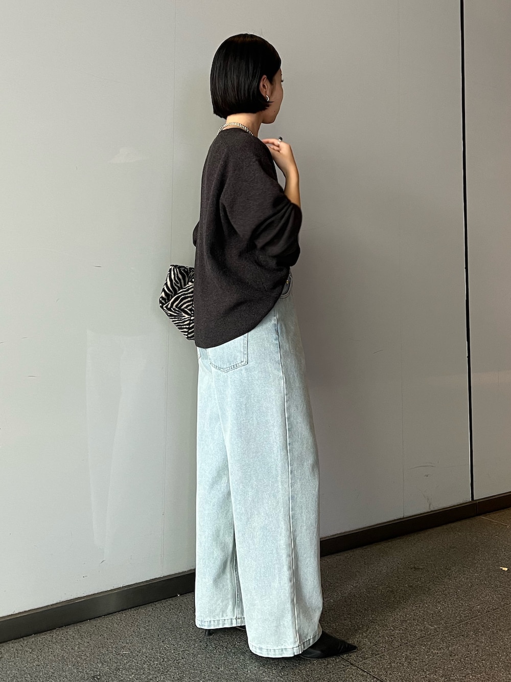グレー系のニット/セーター、ブルー系のデニムパンツ、グレー系のトートバッグを着用したレディースの秋コーディネートの2枚目の写真