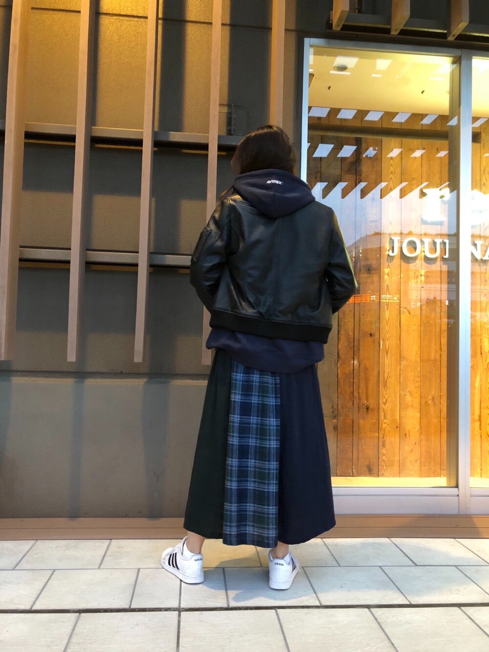 グリーン系のスカート、ブルー系のパーカー、ブラック系のMA-1を着用したレディースの秋コーディネートの2枚目の写真