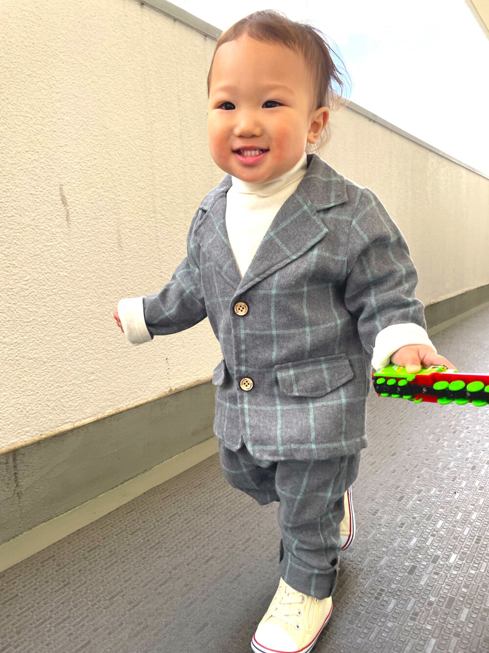 グレー系のスーツセット、ホワイト系のスニーカー、ホワイト系のTシャツ/カットソーを着用したキッズの冬コーディネートの2枚目の写真