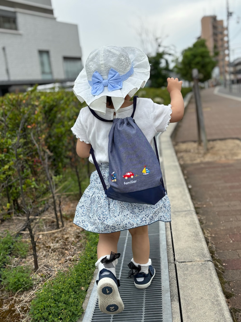 ホワイト系のTシャツ/カットソー、ブルー系のサンダル、ホワイト系のハットを着用したキッズの春コーディネートの3枚目の写真