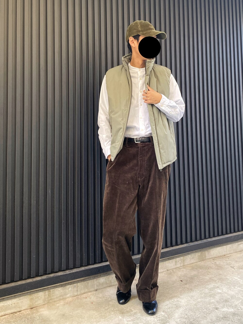 ブラック系のドレスシューズ、ブラウン系のパンツ、グリーン系のベストを着用したメンズの冬コーディネートの2枚目の写真