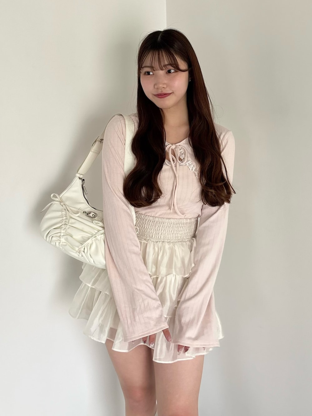 ピンク系のアンサンブル、ホワイト系のショルダーバッグ、ホワイト系のスカートを着用したレディースの春コーディネートの3枚目の写真