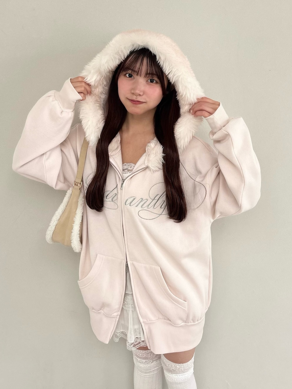 ピンク系のパーカー、ホワイト系のショルダーバッグ、ホワイト系のスカートを着用したレディースの秋コーディネートの2枚目の写真