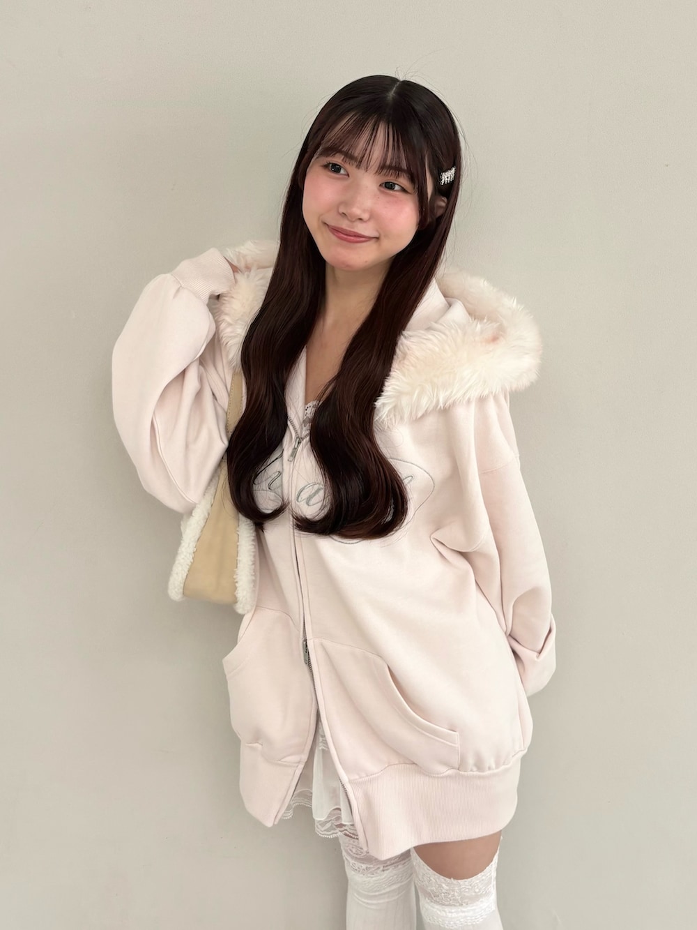 ピンク系のパーカー、ホワイト系のショルダーバッグ、ホワイト系のスカートを着用したレディースの秋コーディネートの3枚目の写真