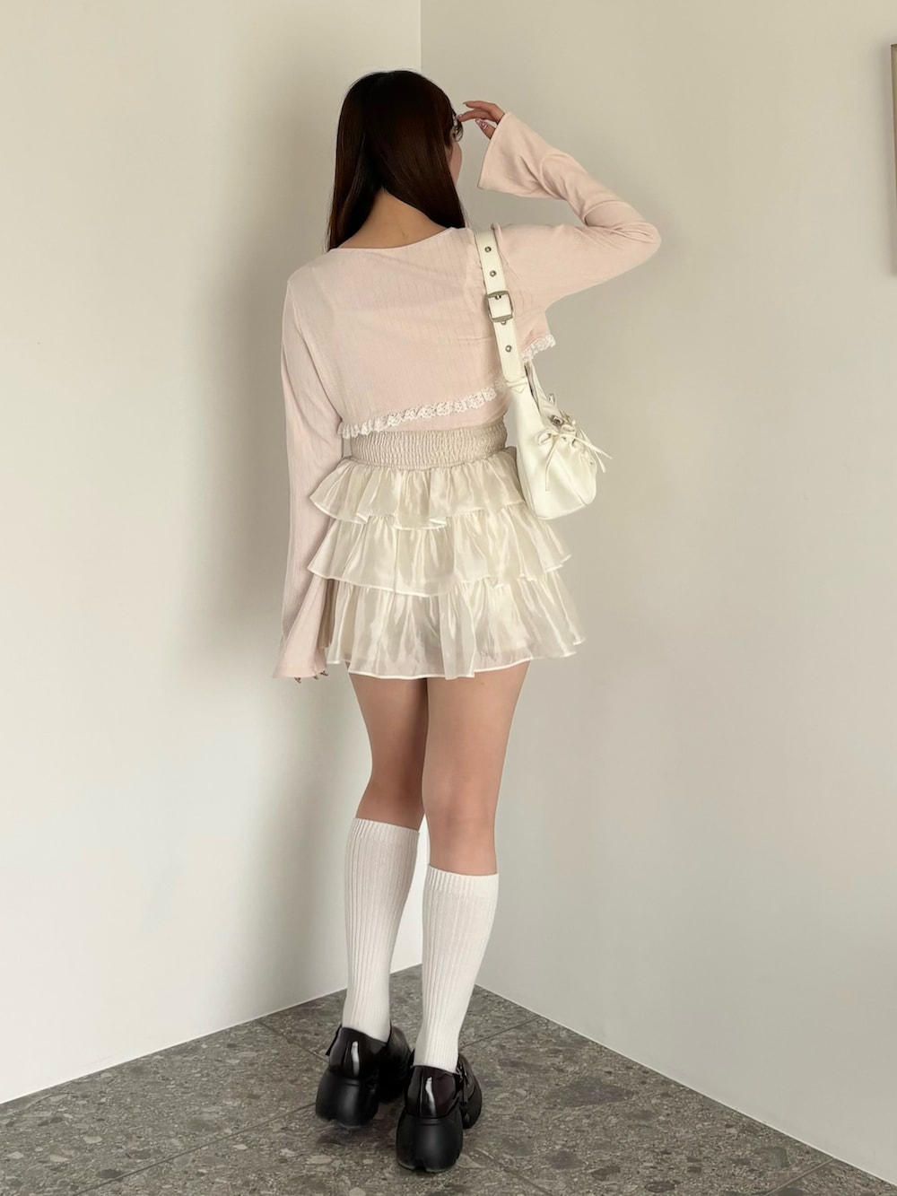 ピンク系のアンサンブル、ホワイト系のショルダーバッグ、ホワイト系のスカートを着用したレディースの春コーディネートの2枚目の写真