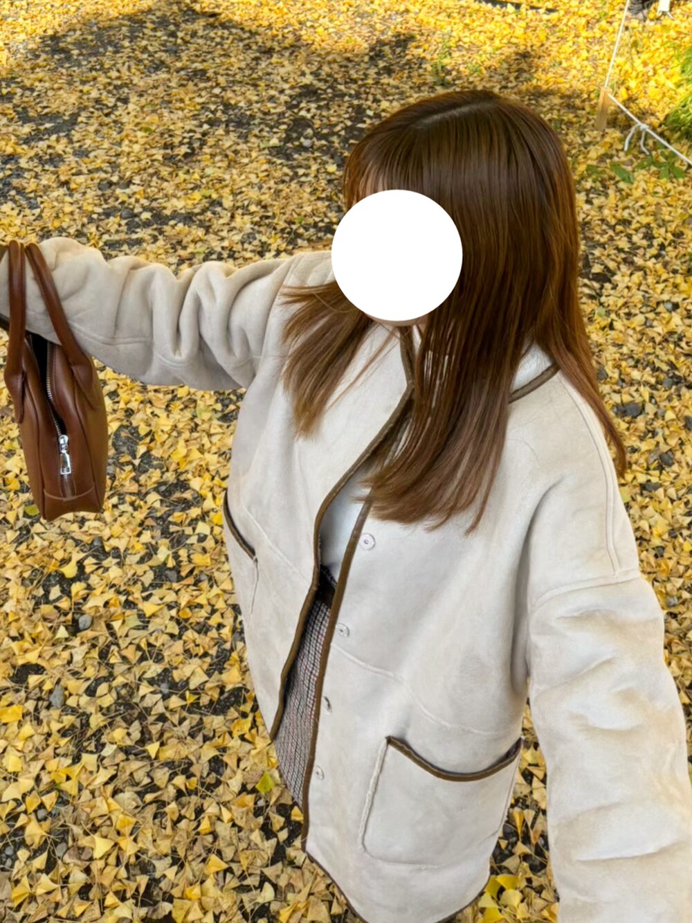 ブラウン系のボストンバッグ、ベージュ系のノーカラーコート、ブラック系のブーツを着用したレディースの春コーディネートの3枚目の写真