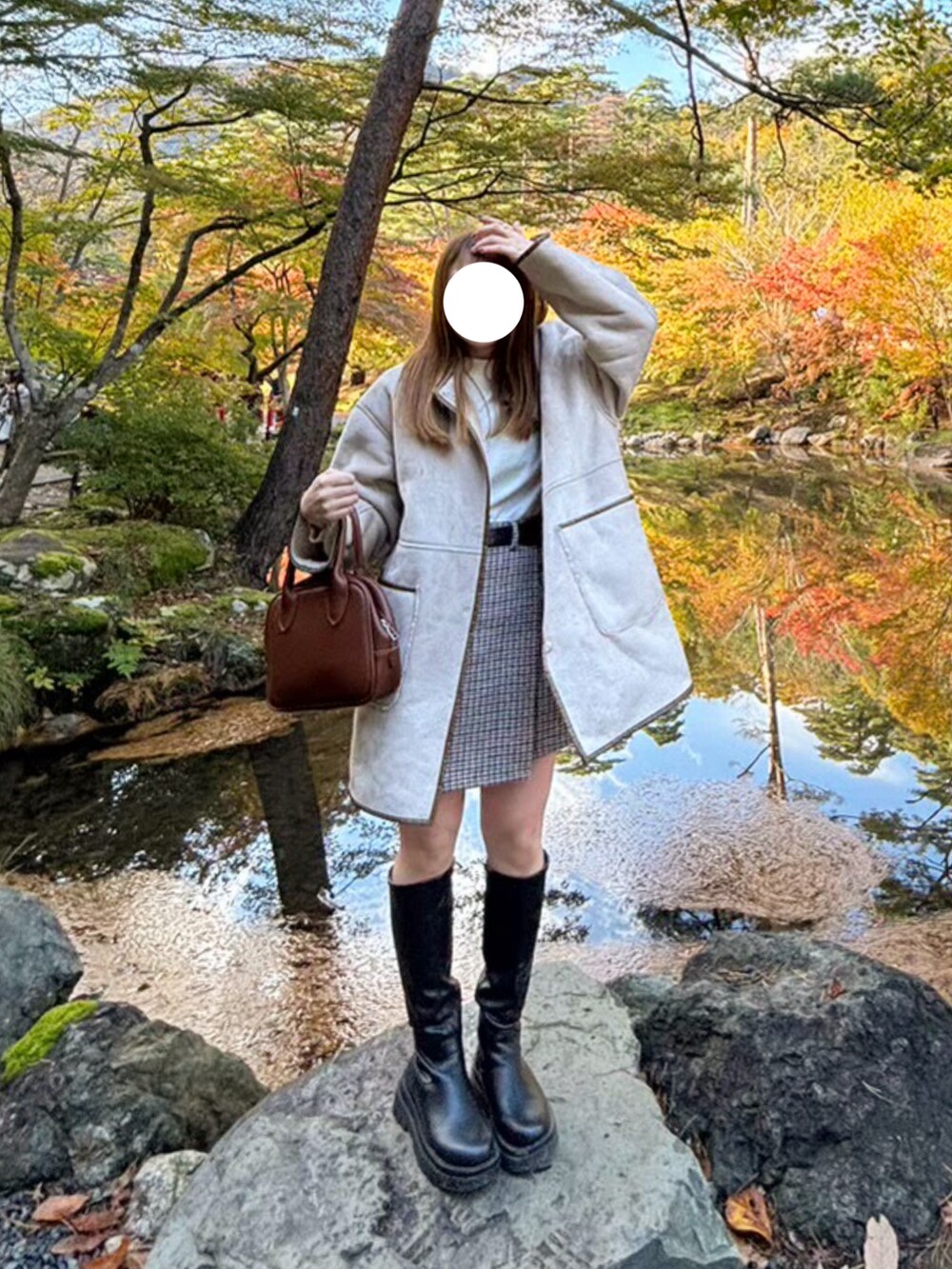 ブラウン系のボストンバッグ、ベージュ系のノーカラーコート、ブラック系のブーツを着用したレディースの春コーディネートの2枚目の写真