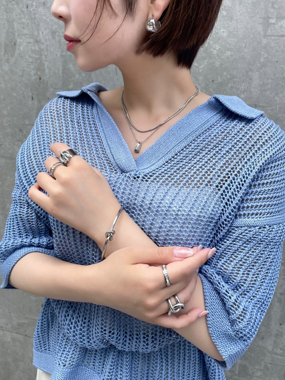 ブルー系のトップス、ホワイト系のカーゴパンツ、シルバー系のピアス（両耳用）を着用したレディースの夏コーディネートの3枚目の写真