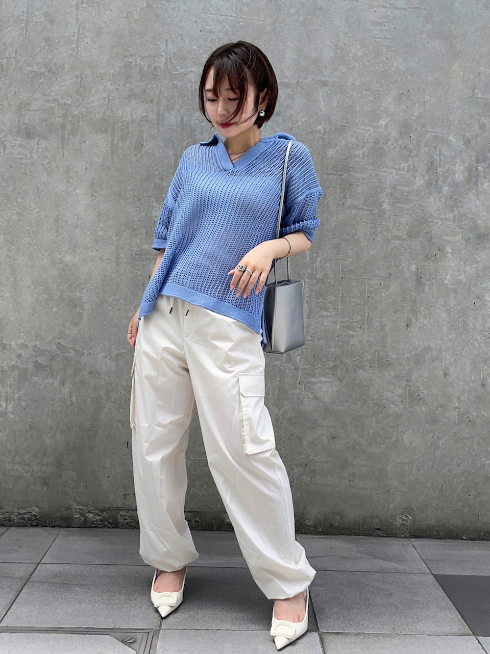 ブルー系のトップス、ホワイト系のカーゴパンツ、シルバー系のピアス（両耳用）を着用したレディースの夏コーディネートの2枚目の写真