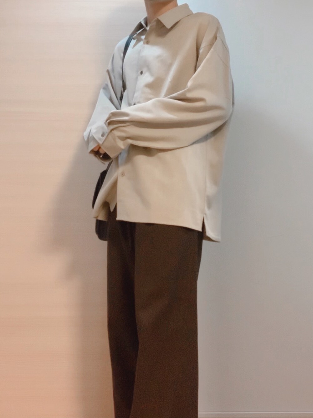 ブラウン系のスラックス、ベージュ系のシャツ/ブラウス、ブラック系のショルダーバッグを着用したメンズの秋コーディネートの2枚目の写真