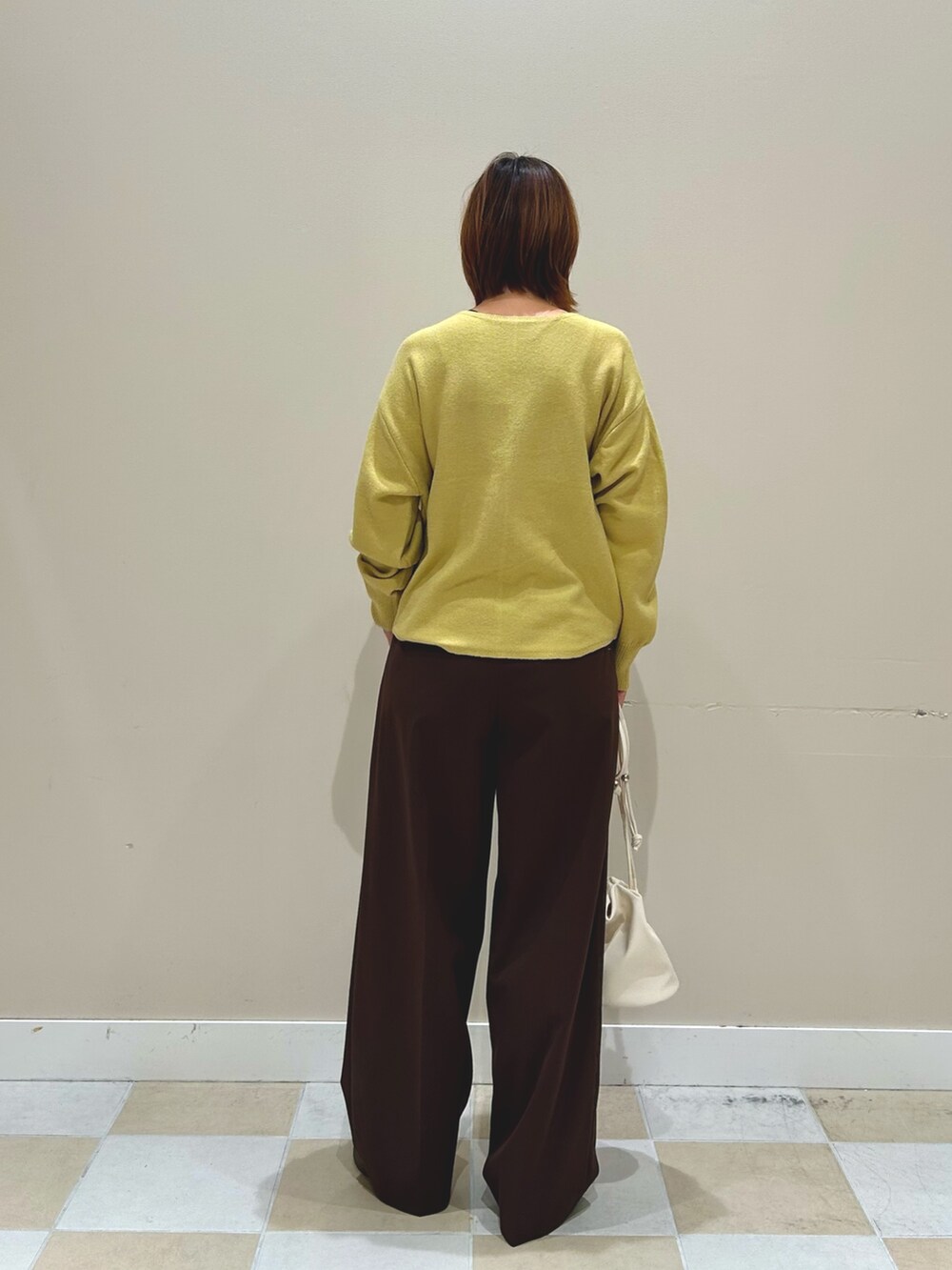 イエロー系のニット/セーター、ホワイト系のショルダーバッグ、ブラウン系のその他パンツを着用したレディースの秋コーディネートの3枚目の写真