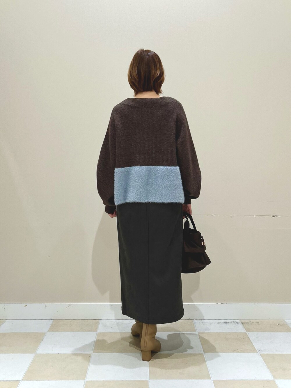 ブラウン系のニット/セーター、ブラック系のスカート、ベージュ系のブーツを着用したレディースの秋コーディネートの3枚目の写真