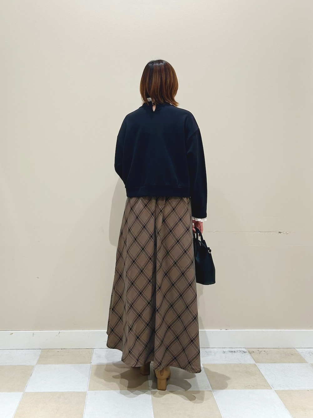 ブラック系のスウェット、ブラウン系のスカート、ブラック系のショルダーバッグを着用したレディースの秋コーディネートの3枚目の写真