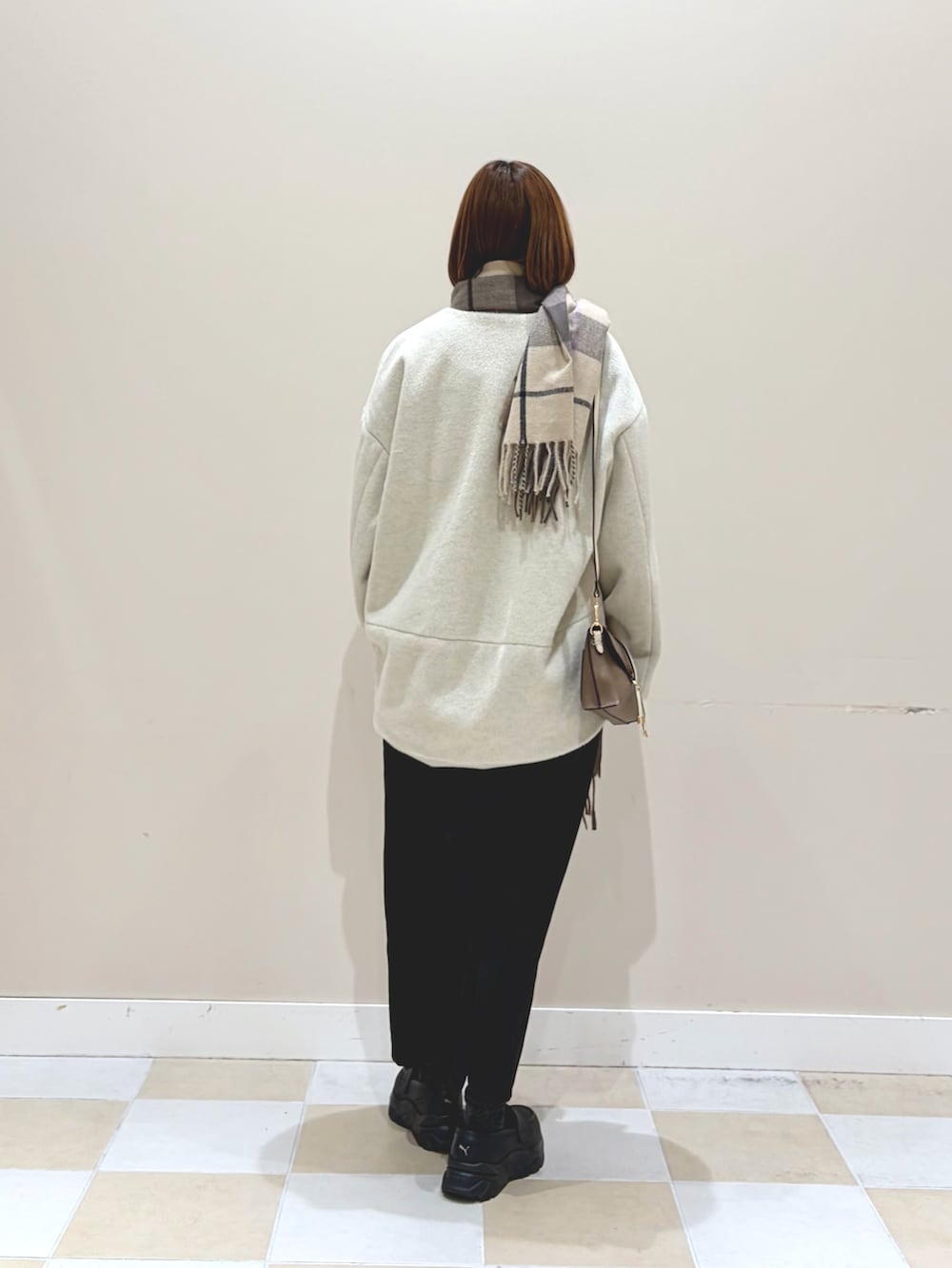 ホワイト系のノーカラージャケット、ブラック系のスカート、ブラウン系のマフラーを着用したレディースの冬コーディネートの3枚目の写真