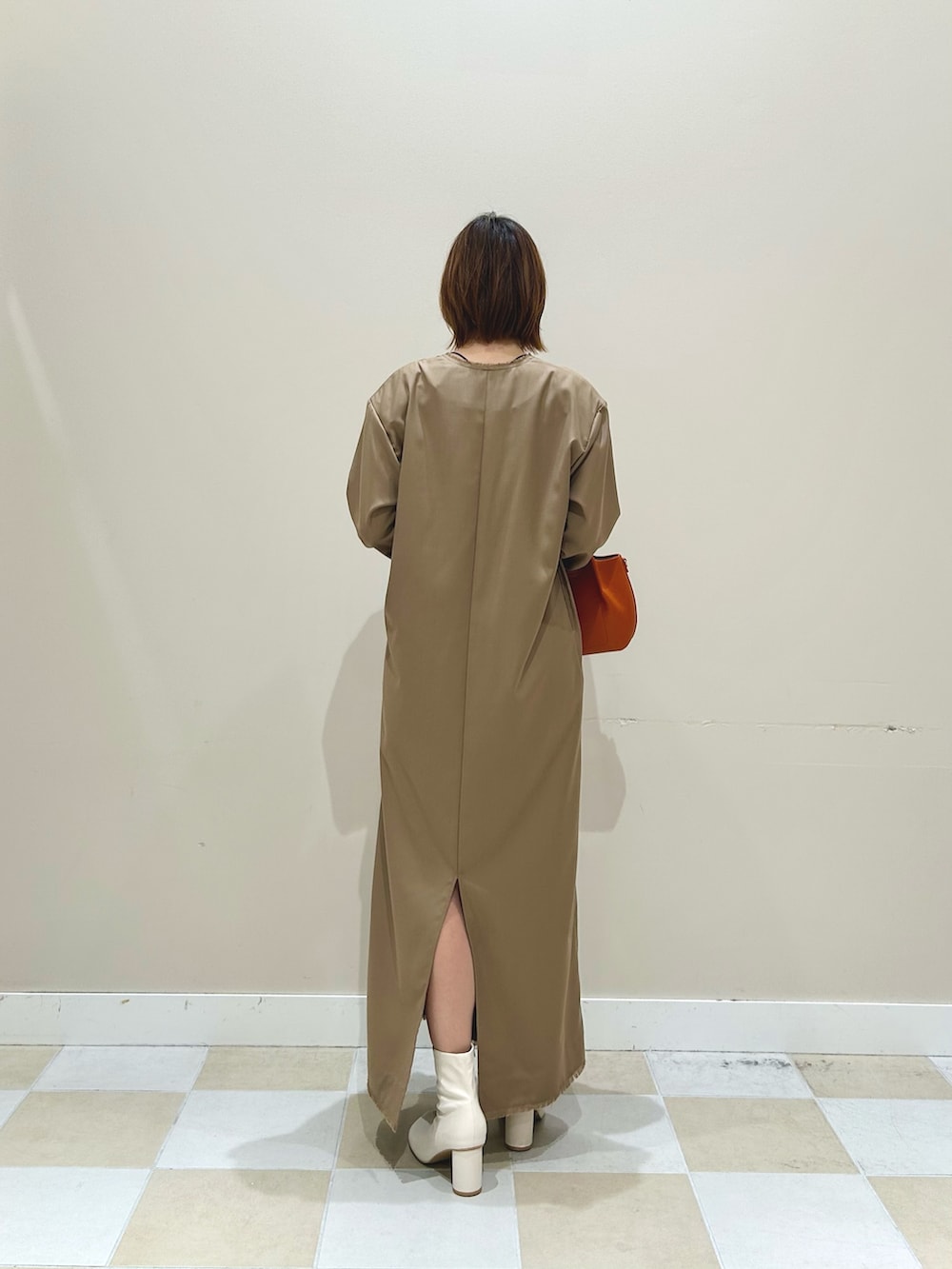 オレンジ系のショルダーバッグ、ベージュ系のワンピースを着用したレディースの秋コーディネートの3枚目の写真