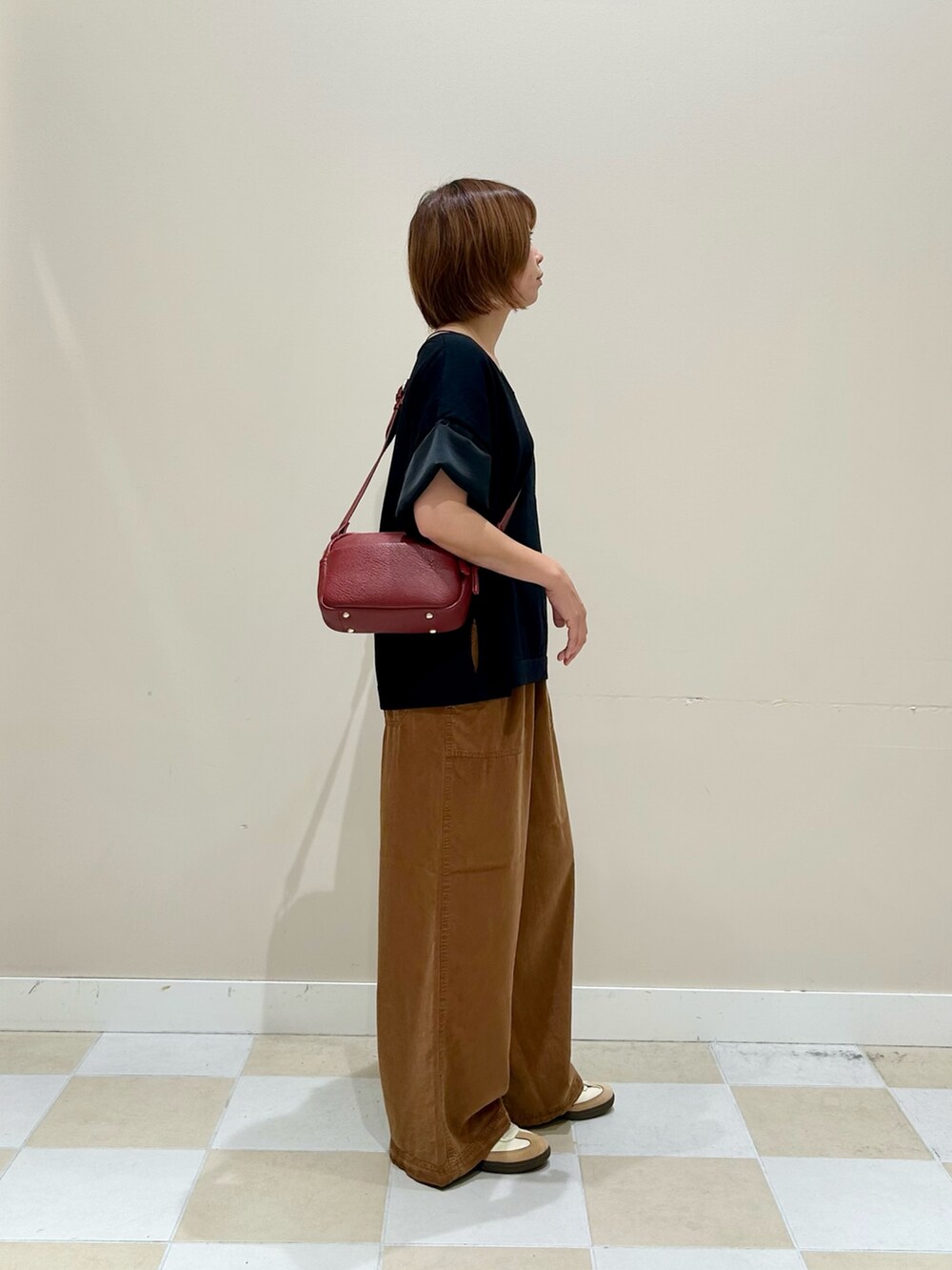 ブラック系のニット/セーター、ブラウン系のその他パンツ、レッド系のショルダーバッグを着用したレディースの秋コーディネートの2枚目の写真