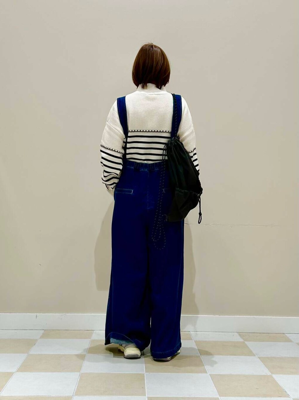 ホワイト系のニット/セーター、ブルー系のサロペット/オーバーオール、ブラック系のバックパック/リュックを着用したレディースの冬コーディネートの3枚目の写真