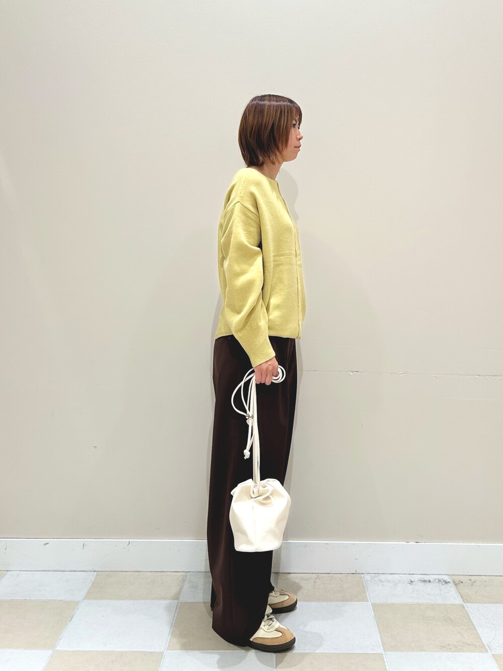 イエロー系のニット/セーター、ホワイト系のショルダーバッグ、ブラウン系のその他パンツを着用したレディースの秋コーディネートの2枚目の写真