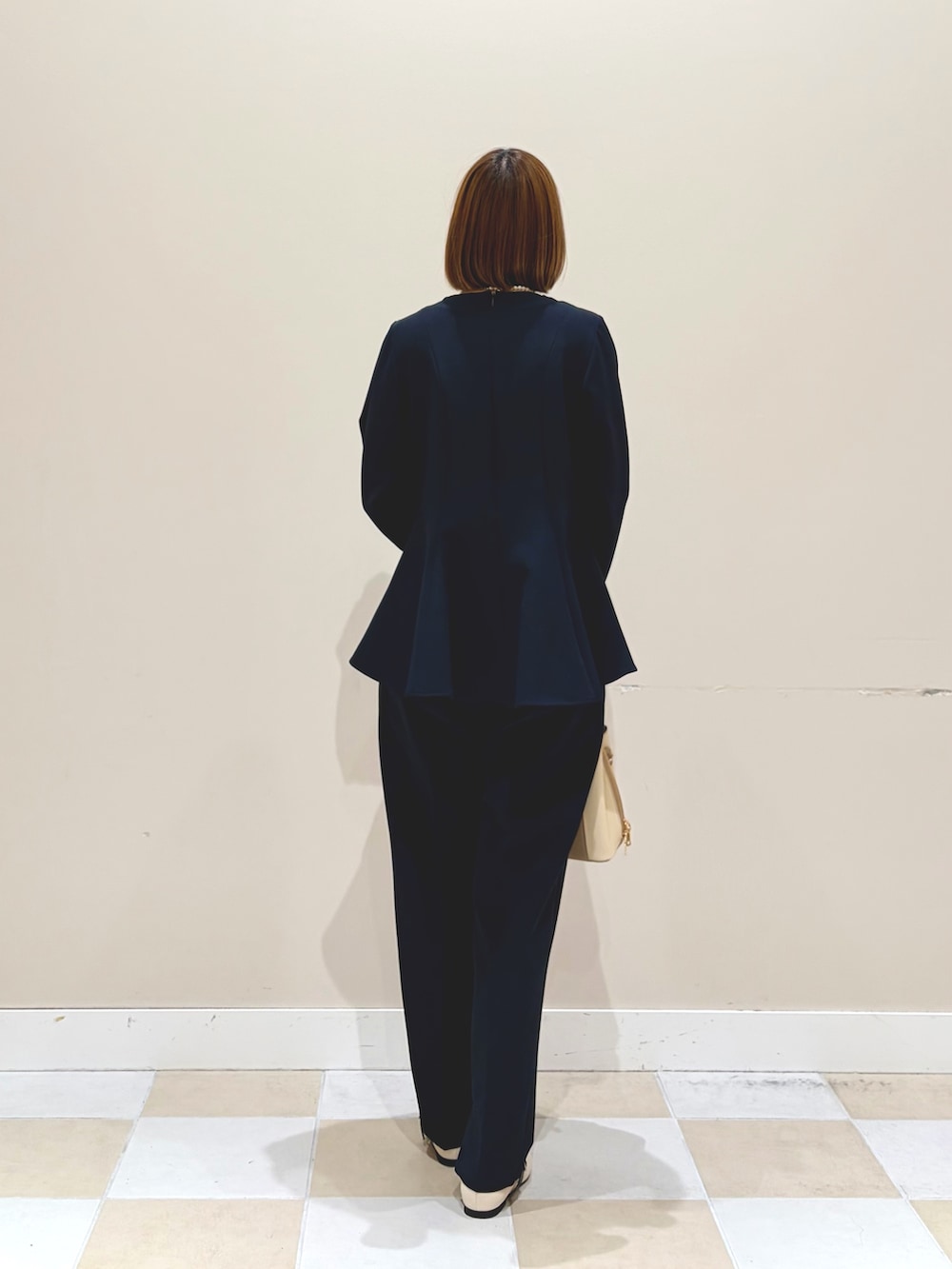 ホワイト系のハンドバッグ、ブルー系のセットアップ、ホワイト系のネックレスを着用したレディースの春コーディネートの3枚目の写真