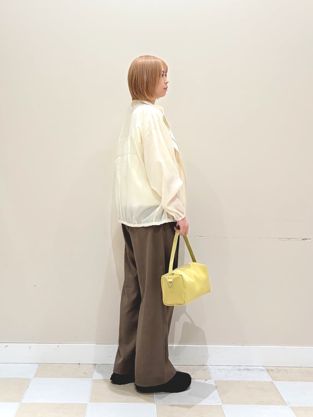 ホワイト系のブルゾン、グリーン系のその他パンツ、イエロー系のトートバッグを着用したレディースの春コーディネートの2枚目の写真