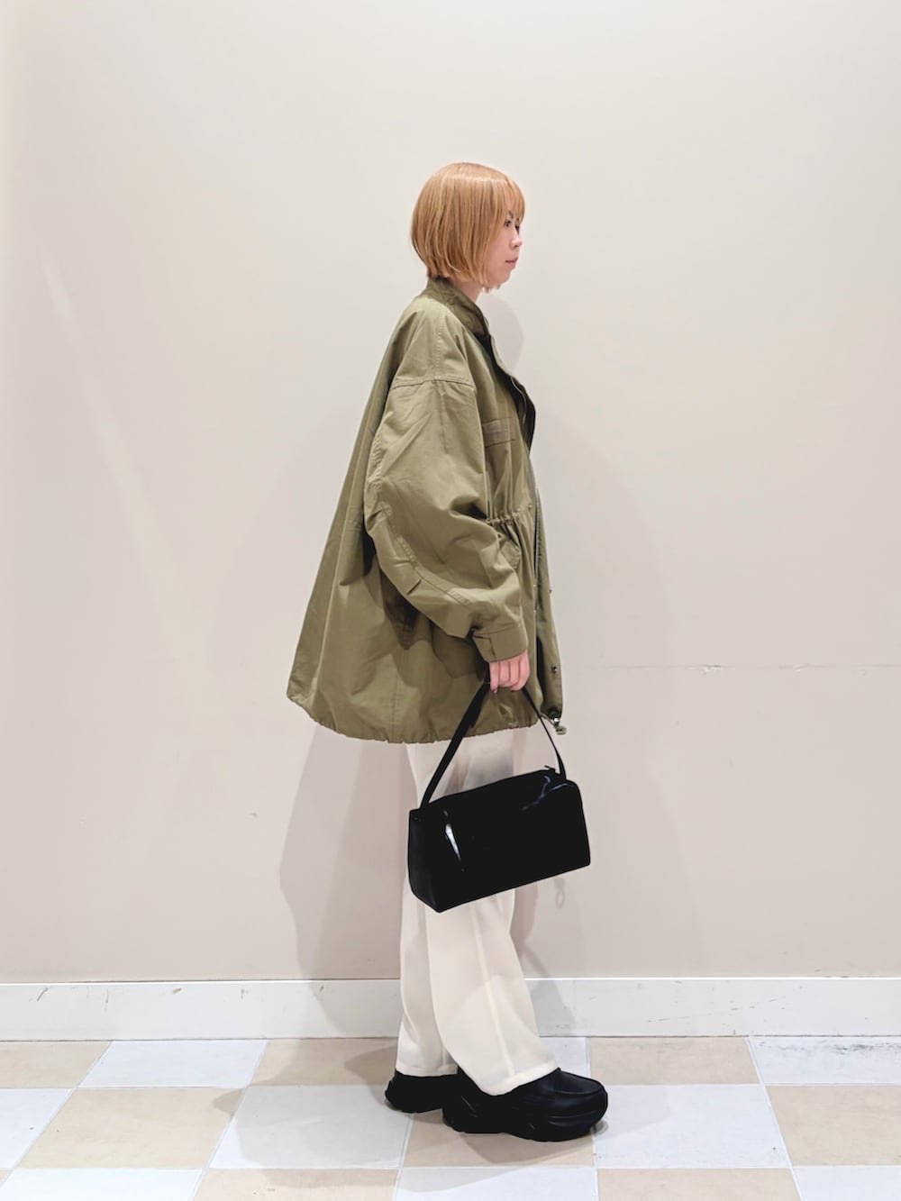 ホワイト系のその他パンツ、グリーン系のモッズコート、ベージュ系のニット/セーターを着用したレディースの春コーディネートの2枚目の写真