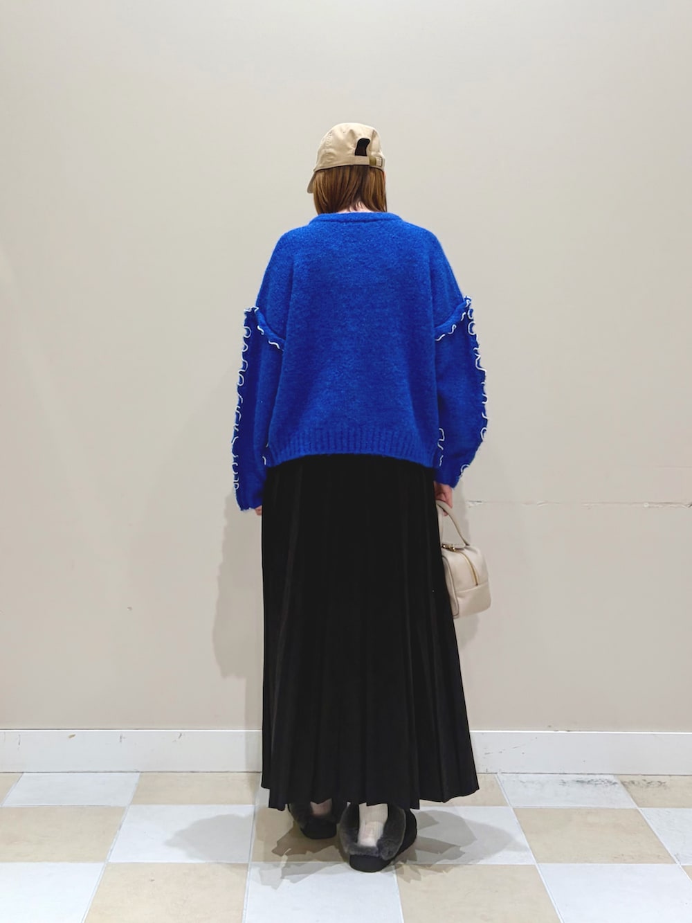 ブルー系のニット/セーター、ブラック系のスカート、ベージュ系のキャップを着用したレディースの冬コーディネートの3枚目の写真