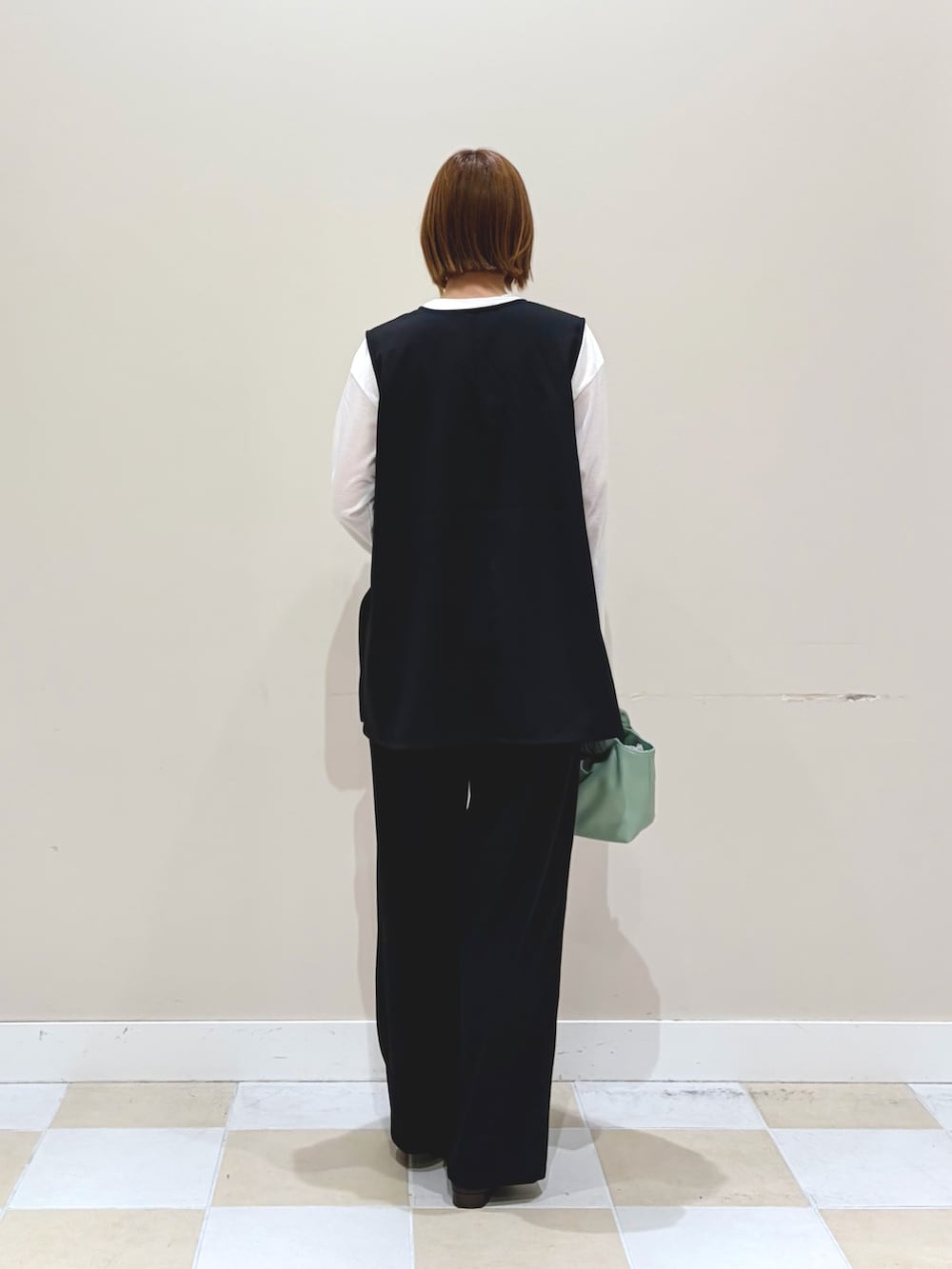 ブラック系のセットアップ、グリーン系のショルダーバッグ、ホワイト系のネックレスを着用したレディースの冬コーディネートの3枚目の写真