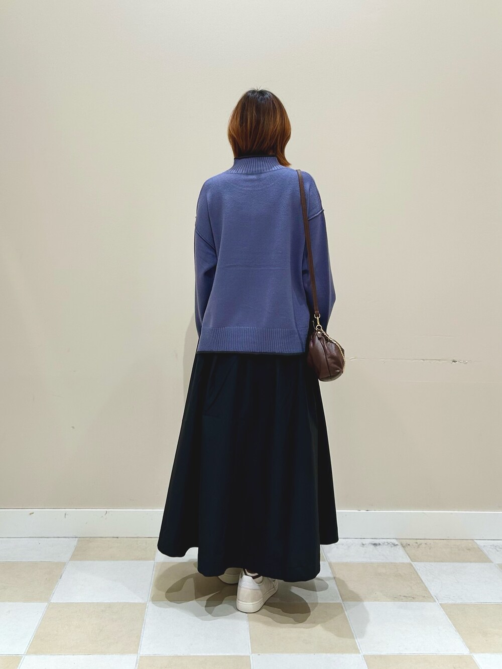 ブラック系のスカート、ブルー系のニット/セーター、ブラウン系のショルダーバッグを着用したレディースの秋コーディネートの3枚目の写真