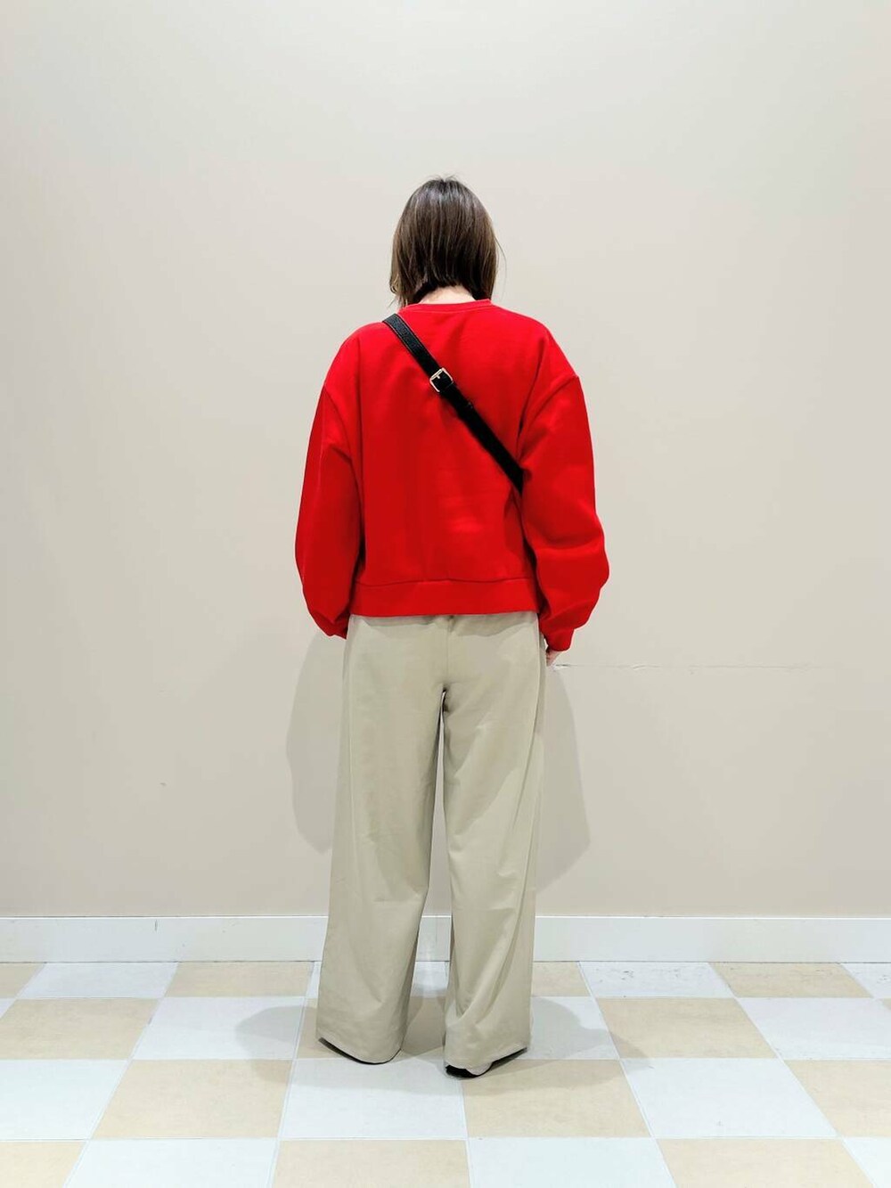 ブラック系のショルダーバッグ、ベージュ系のその他パンツ、レッド系のTシャツ/カットソーを着用したレディースの冬コーディネートの3枚目の写真
